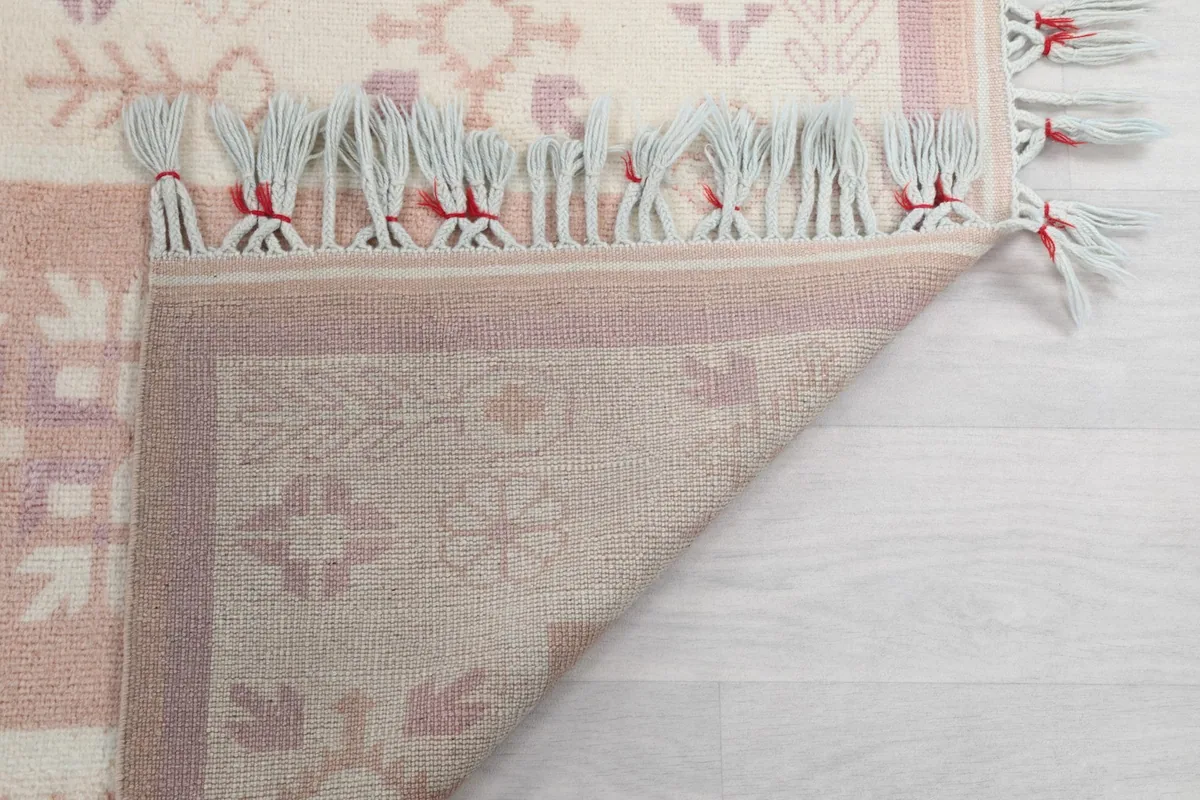 Closer view of the back of the rug, showing the knotting and the cotton foundation, with fringe detail.