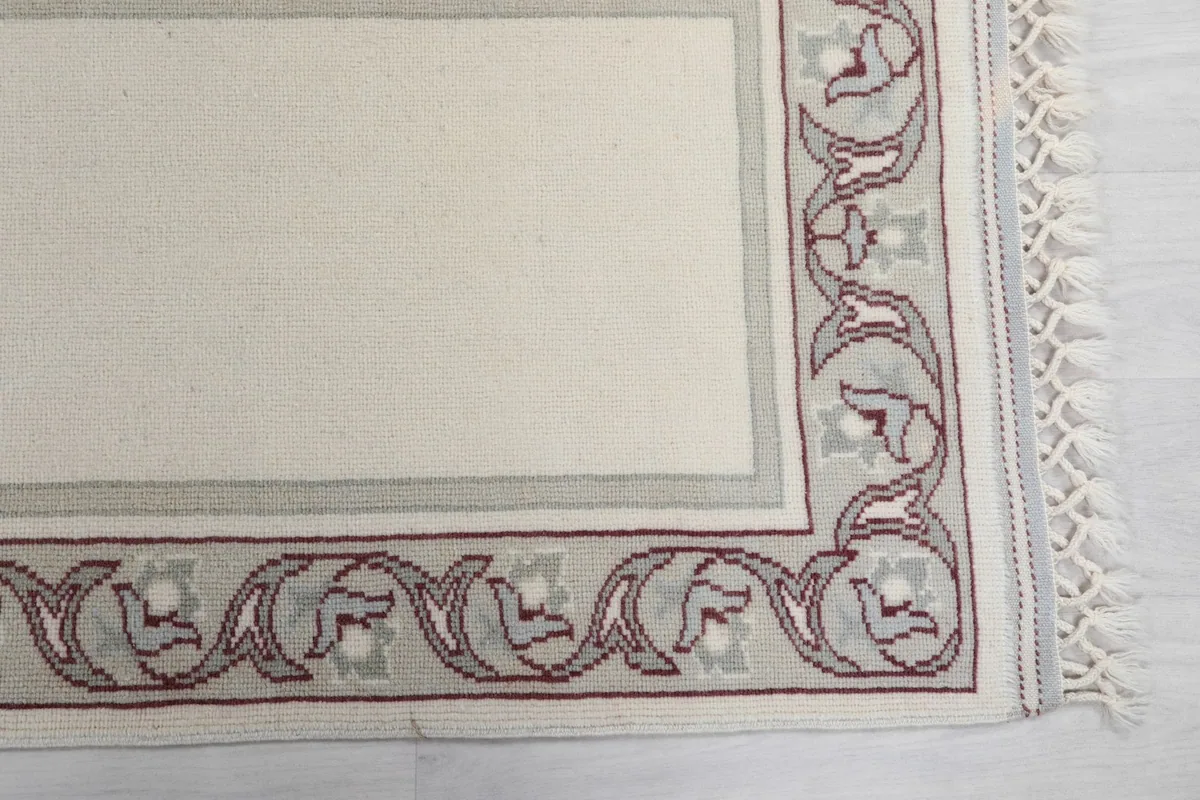 Detailed view of the corner border, showcasing the intricate floral and geometric motifs in rose and gray.