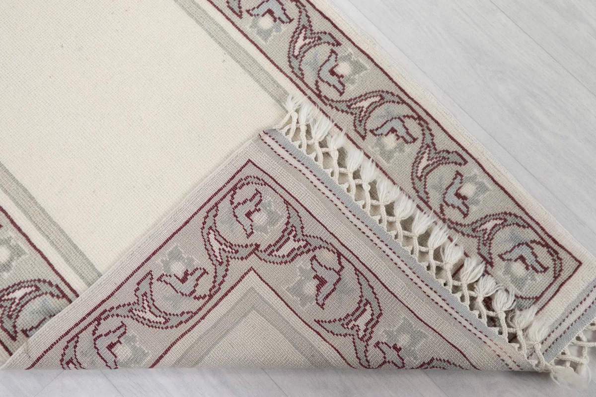 Corner of the runner folded back to show the cotton foundation and the reverse side of the border.