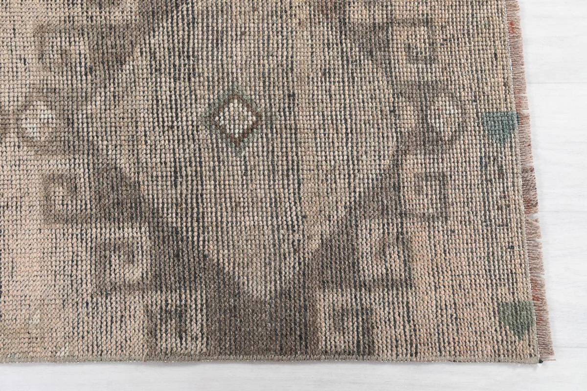 Detailed view of the hand-knotted wool pile and geometric motifs in tan and gray.