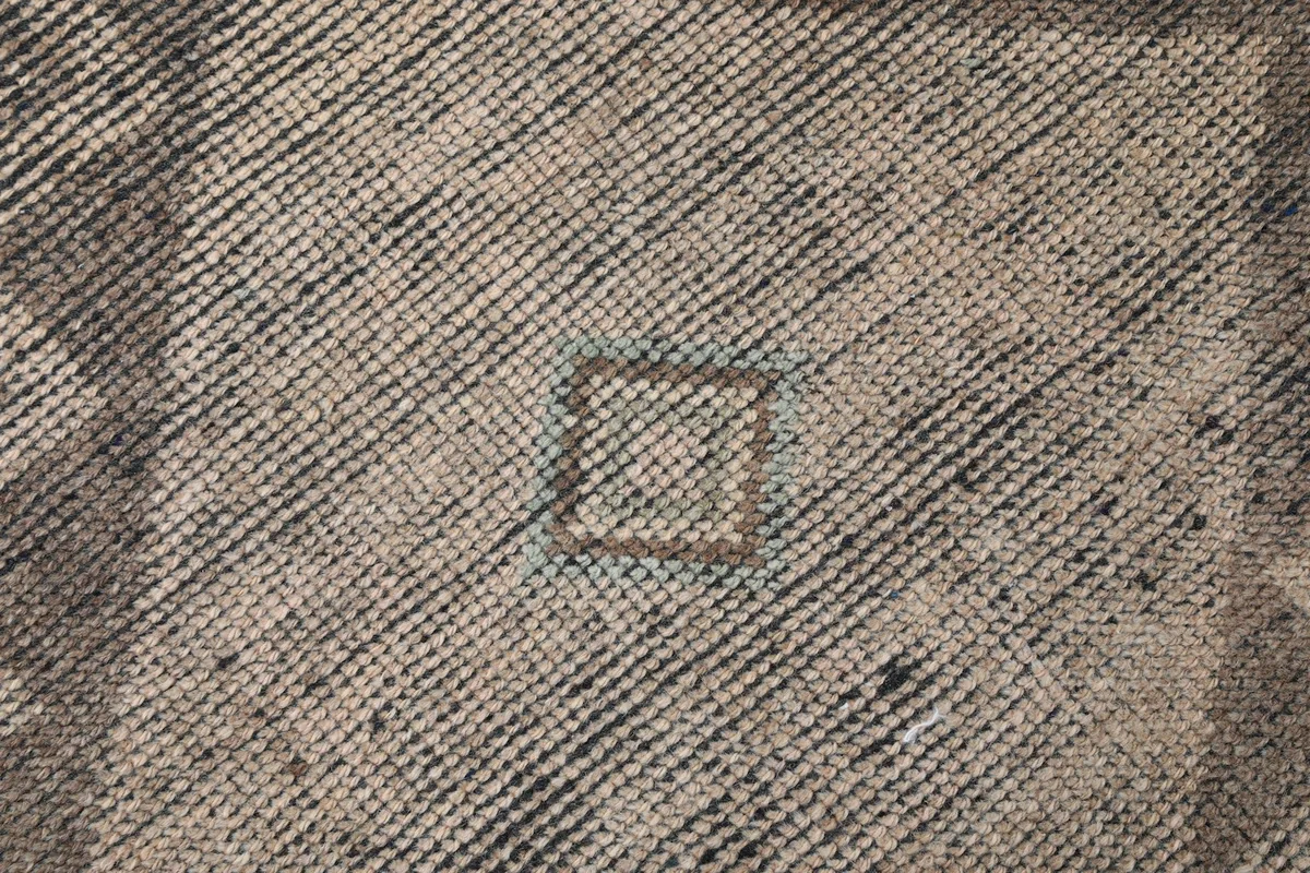 Extreme close-up showing the low pile texture and intricate knotting of the rug.