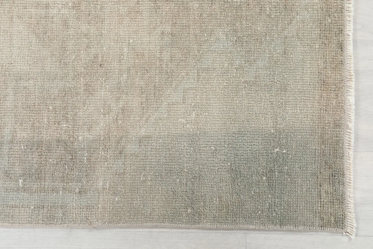 Detailed close-up of the rug's surface, revealing the low pile and subtle blend of beige and gray.