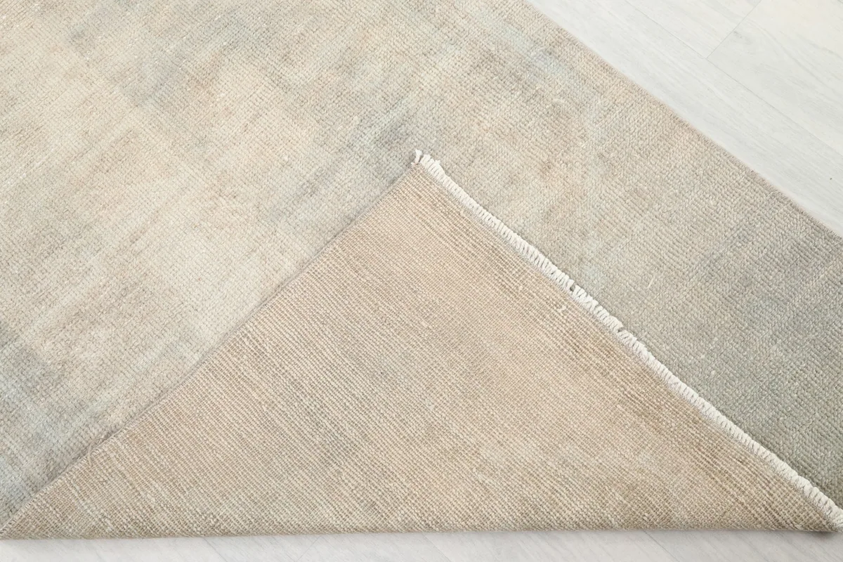 Underside view of the rug, folded to show the cotton foundation and hand-knotted construction.