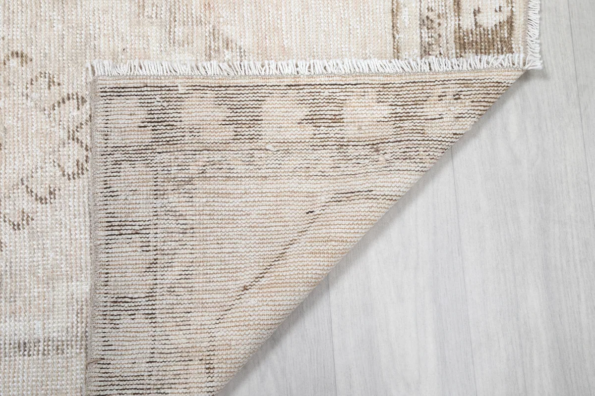 Corner of the Cream Tribal Medallion Rug flipped over, revealing the cotton foundation