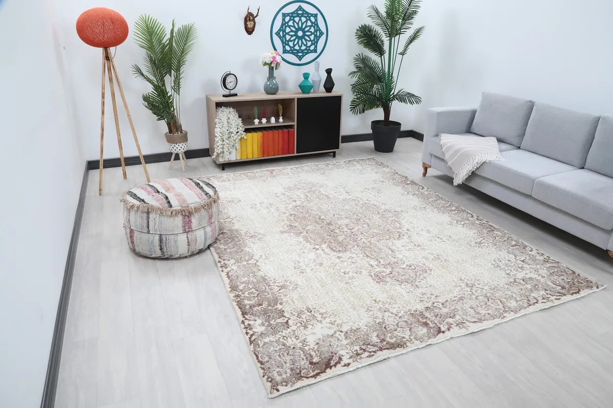 Angle view of the ivory and rose vintage rug in a living room with an ottoman