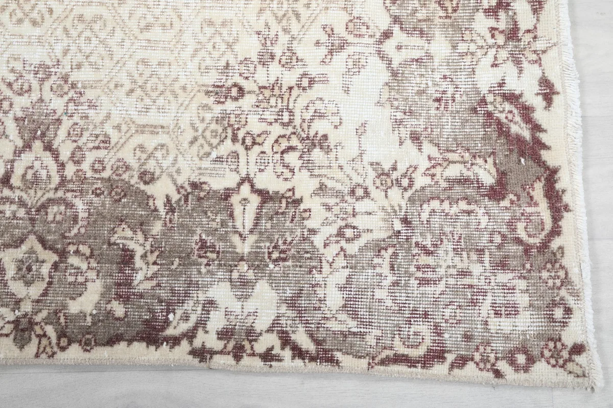 Detailed view of the corner and border of the vintage rug, showing rose and gray motifs