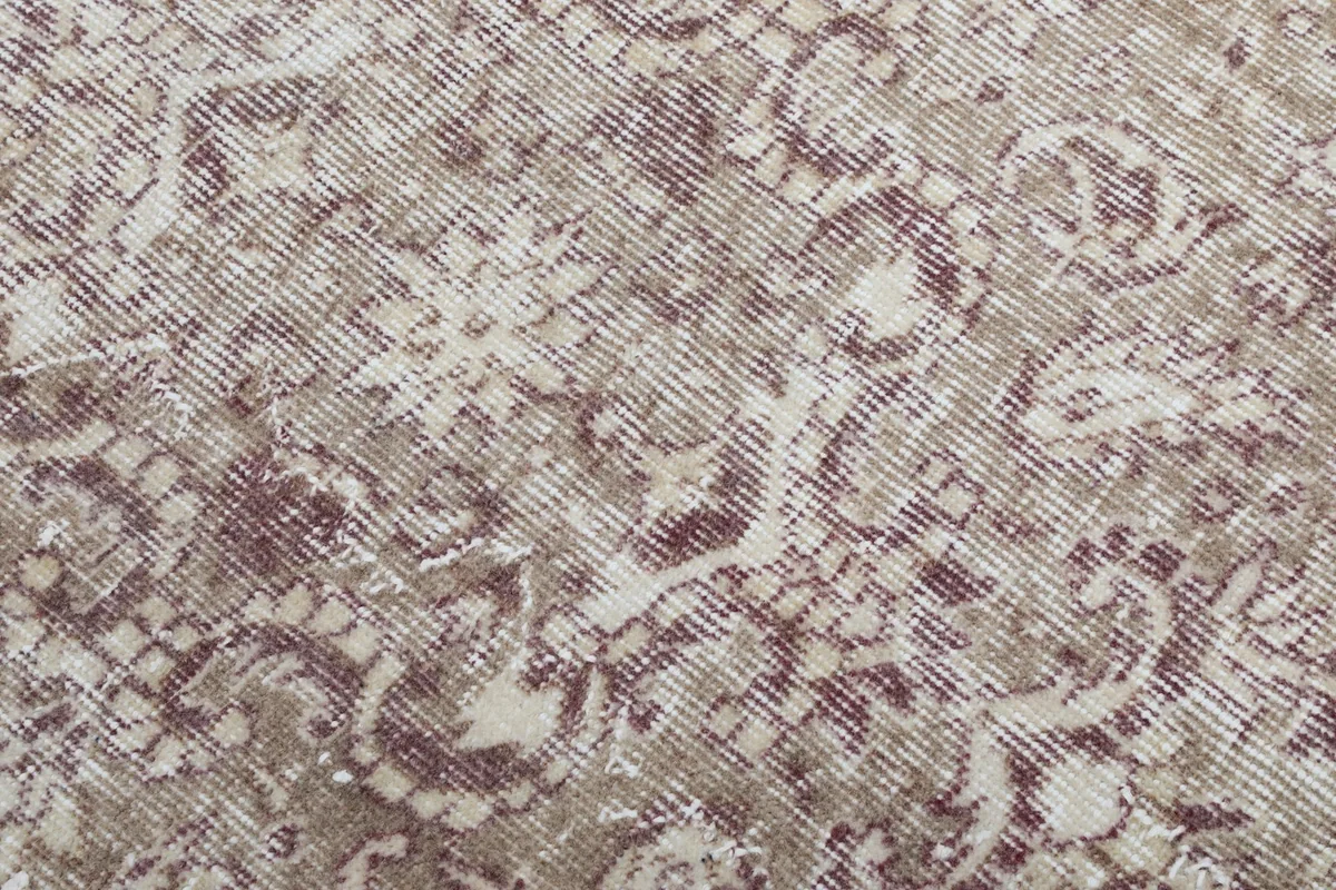 Texture and low pile of the hand-knotted wool rug with faded rose patterns