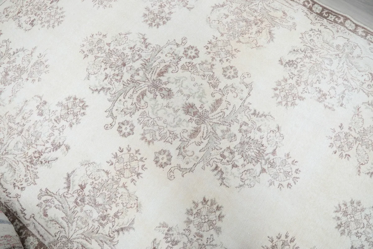Close-up of the central floral medallion motif and surrounding patterns on the ivory rug