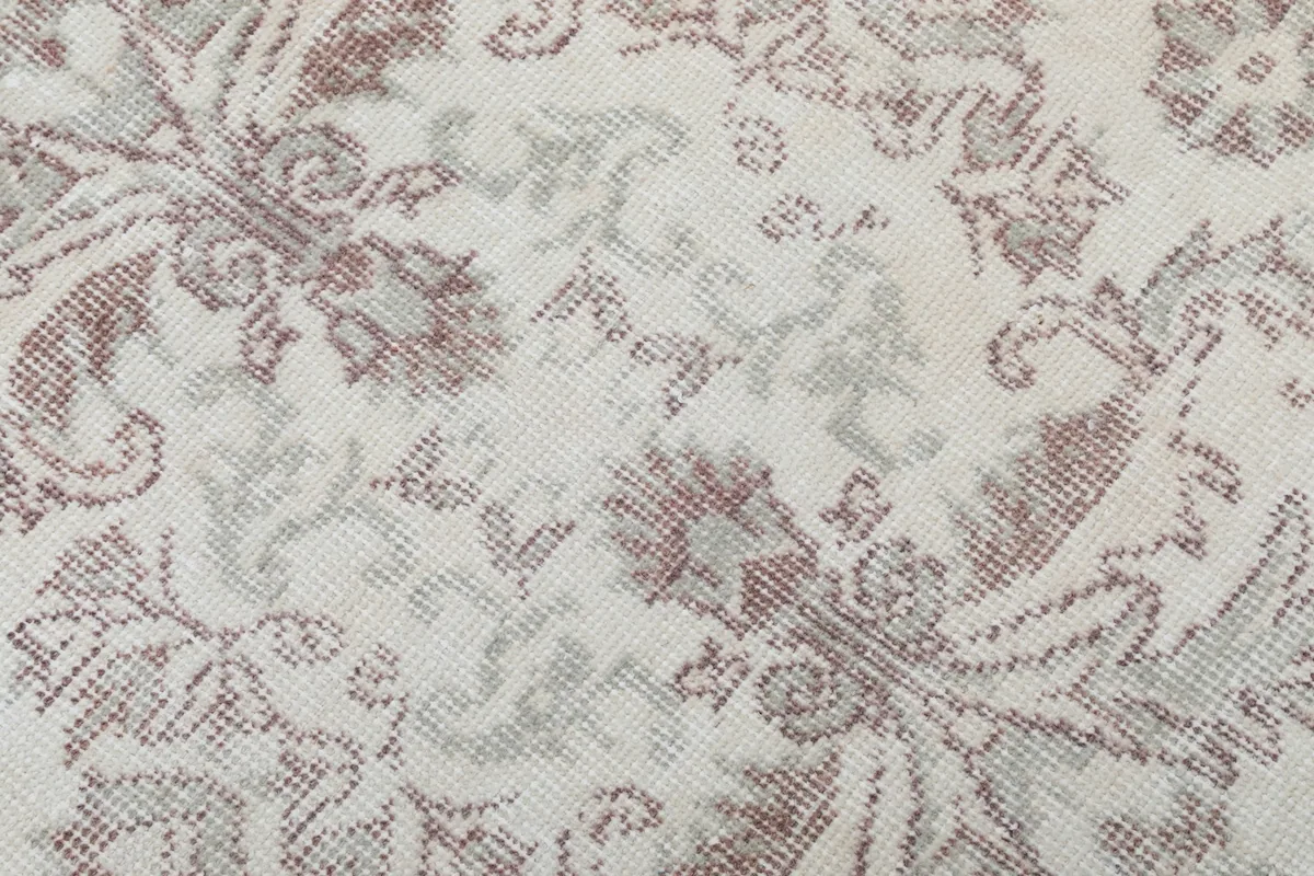 Texture and low pile of the vintage wool rug, highlighting faded brown and beige tones