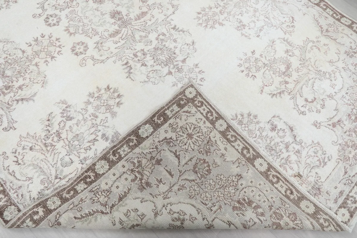 Corner of the rug folded back, revealing the hand-knotted construction and cotton foundation