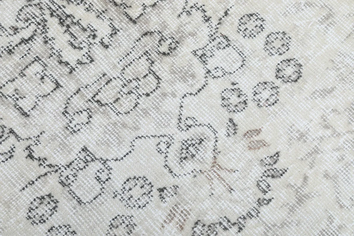 Close-up of the low wool pile and hand-knotted texture with faded gray patterns