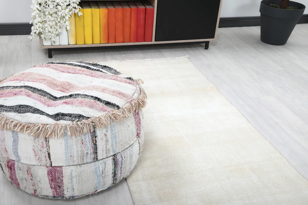 Close-up of the Beige Minimalist Vintage Runner's texture next to a colorful ottoman, showing the subtle distressed patina.
