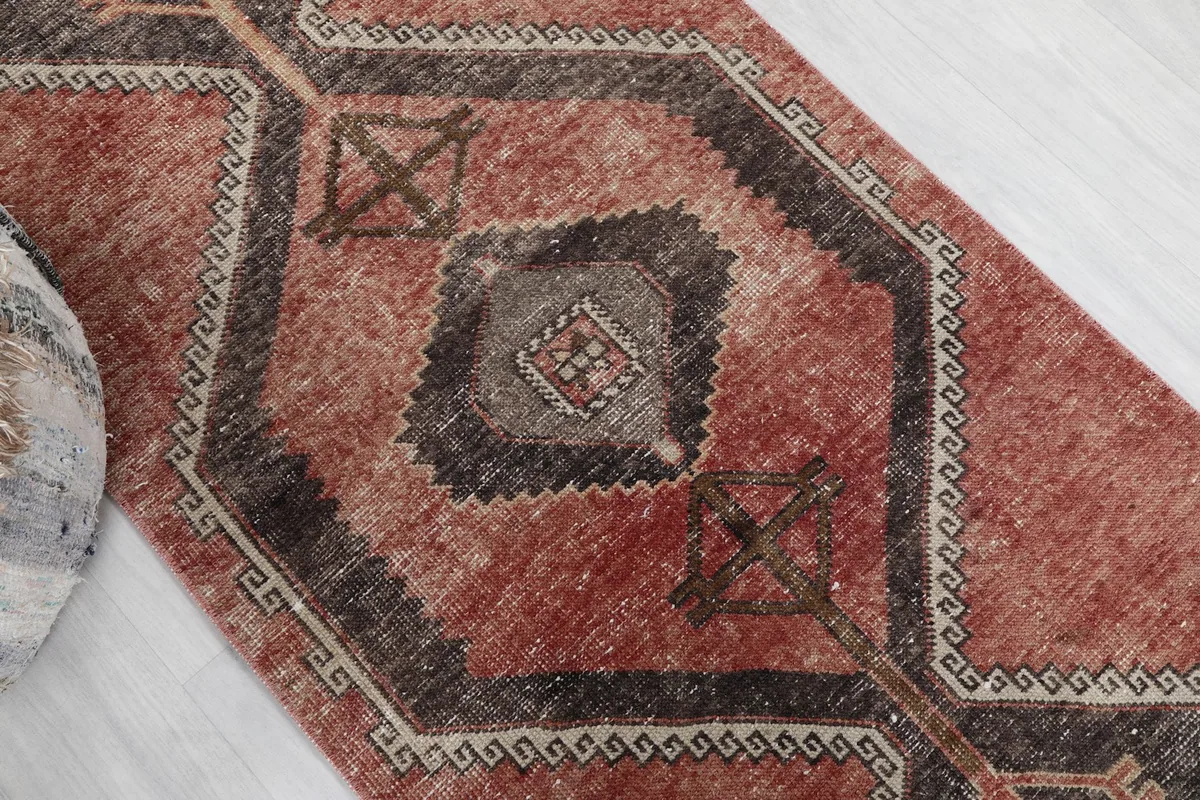 Diagonal view of the runner rug highlighting the central charcoal medallion and rust field