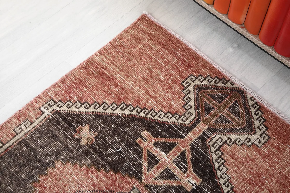 Detailed shot of the rug's end, showcasing the subtle patina and geometric border