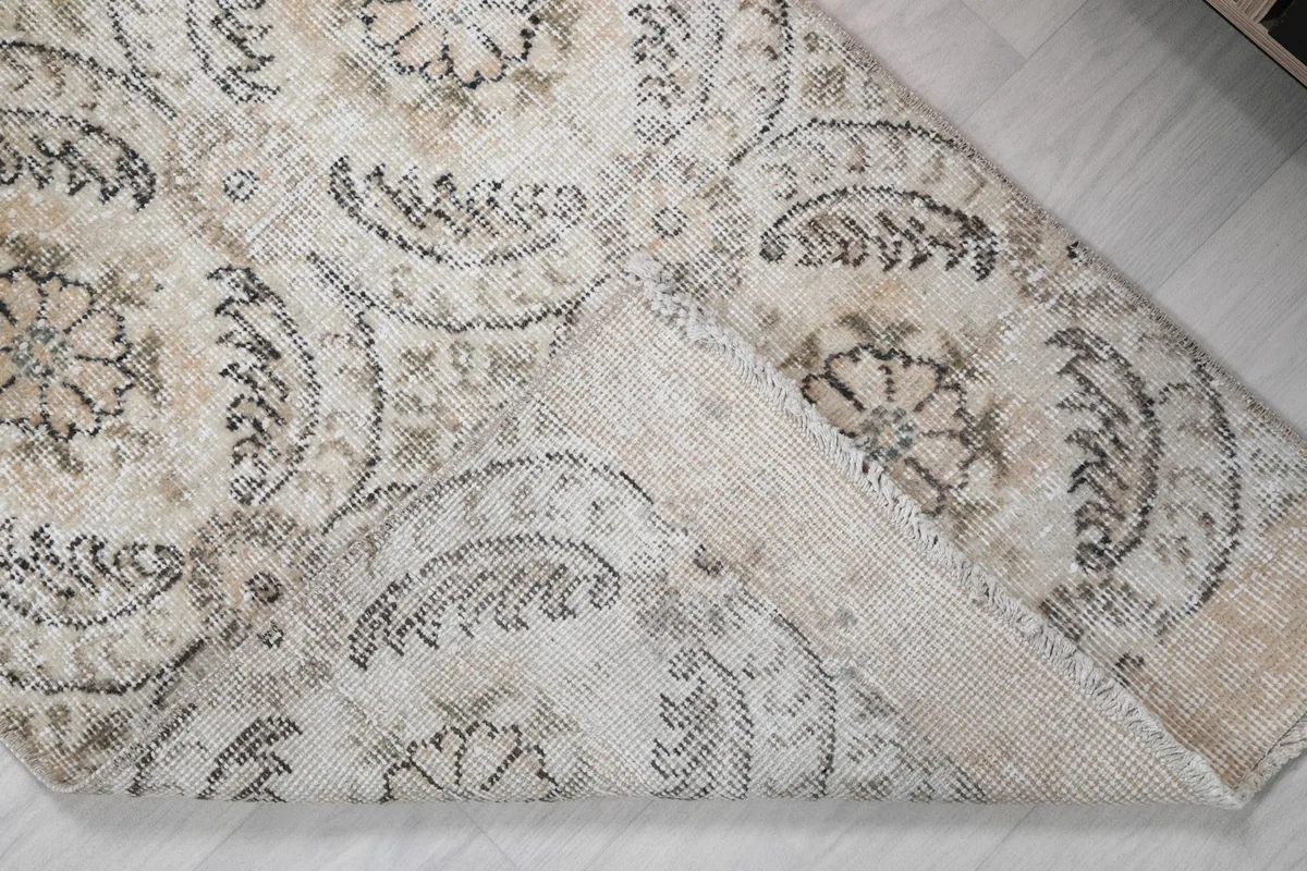 Corner of the rug folded back to reveal the cotton foundation and hand-knotting