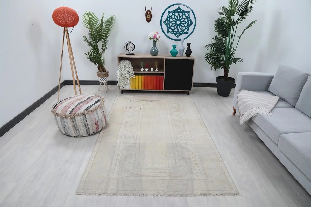 Cream vintage Anatolian rug in a room setting with a light gray couch and decorative elements.