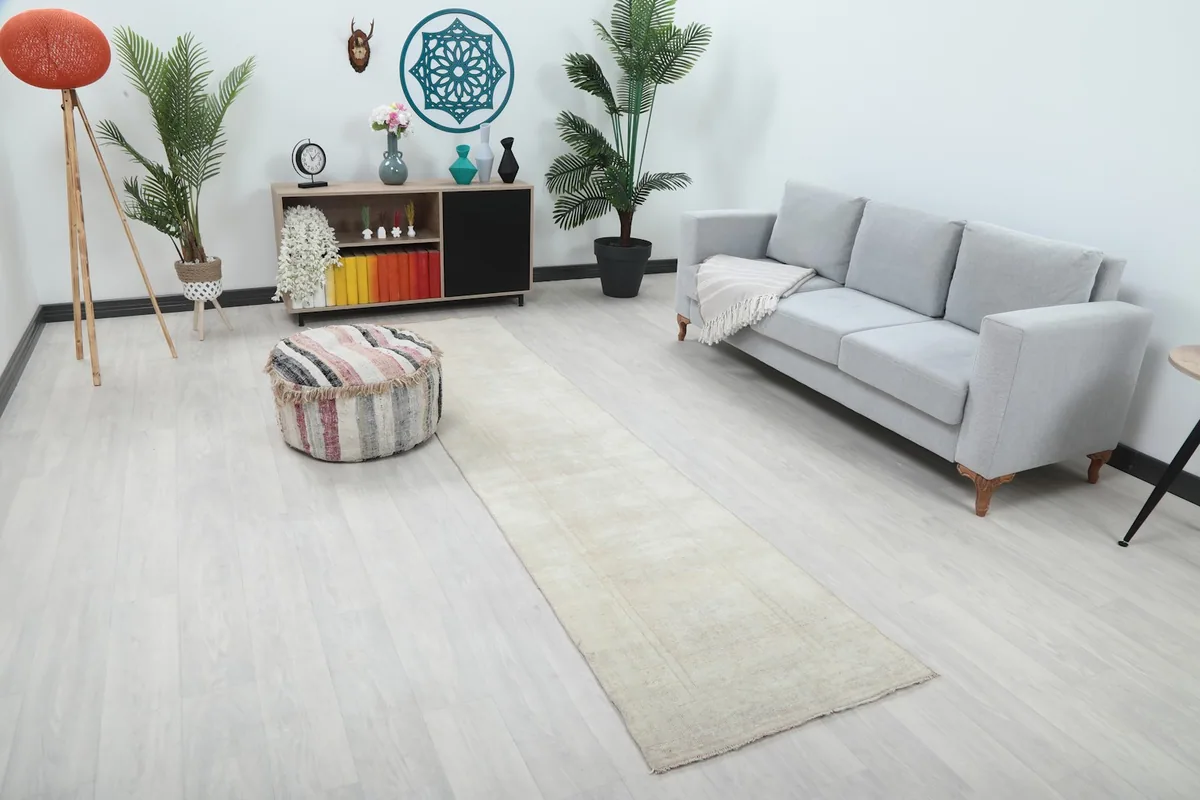 Angled view of the ivory runner rug in a contemporary living space with a sofa and ottoman.