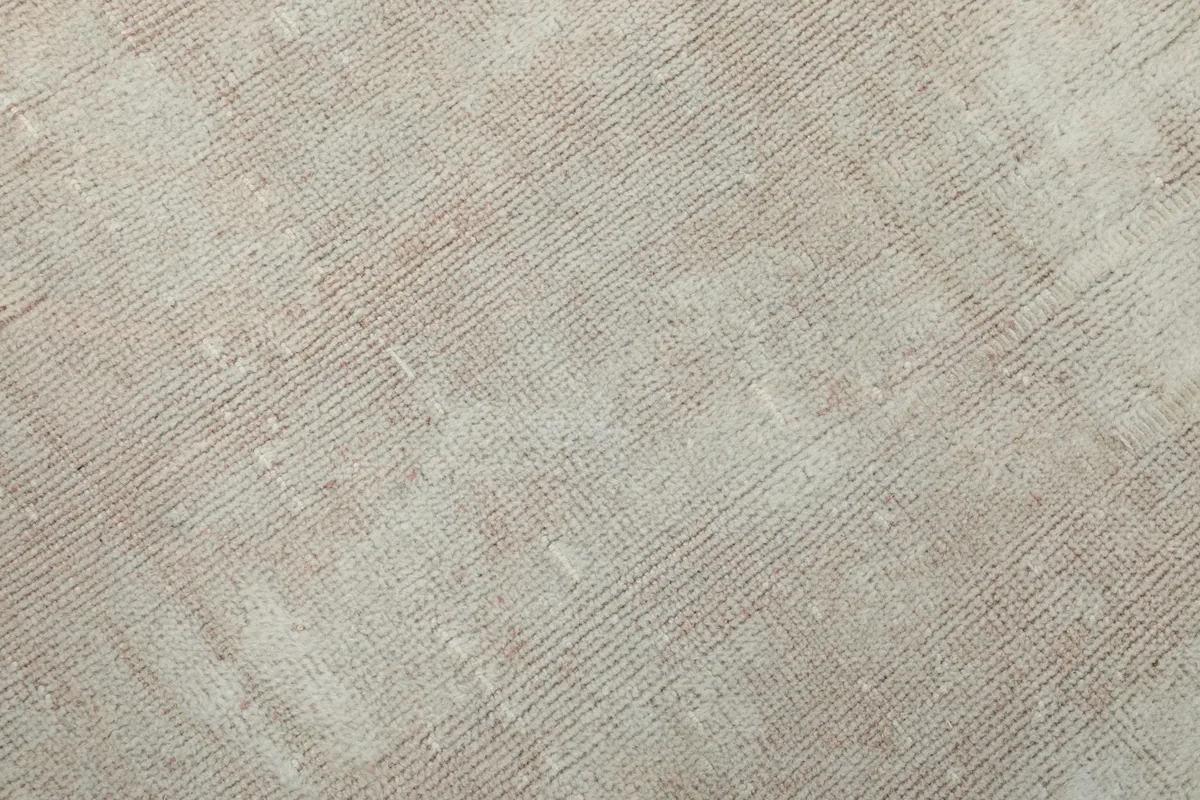 Close-up of the low pile and hand-knotted texture of the vintage ivory rug.