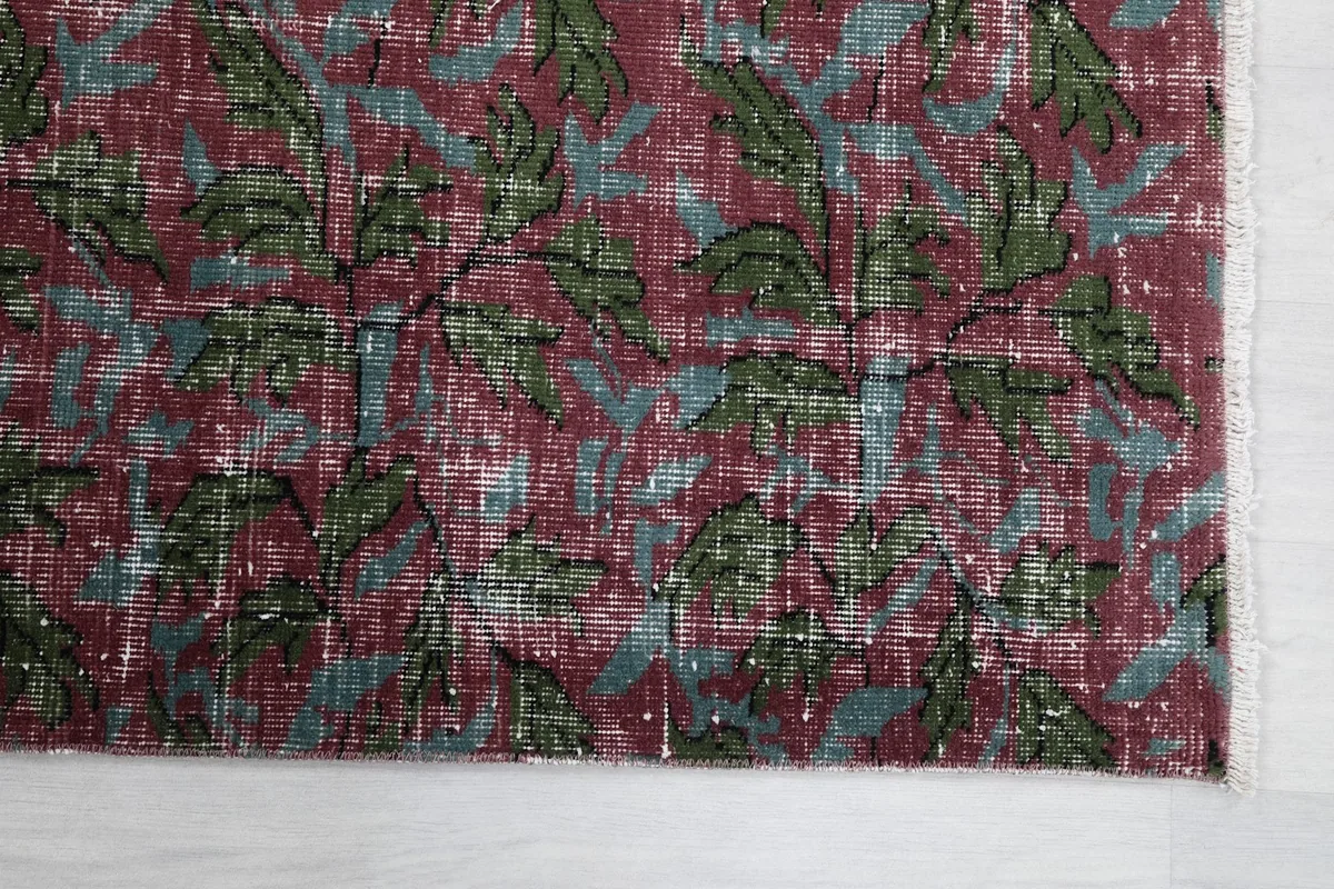 Detailed view of the rose and green floral pattern with visible distressed texture and fringes