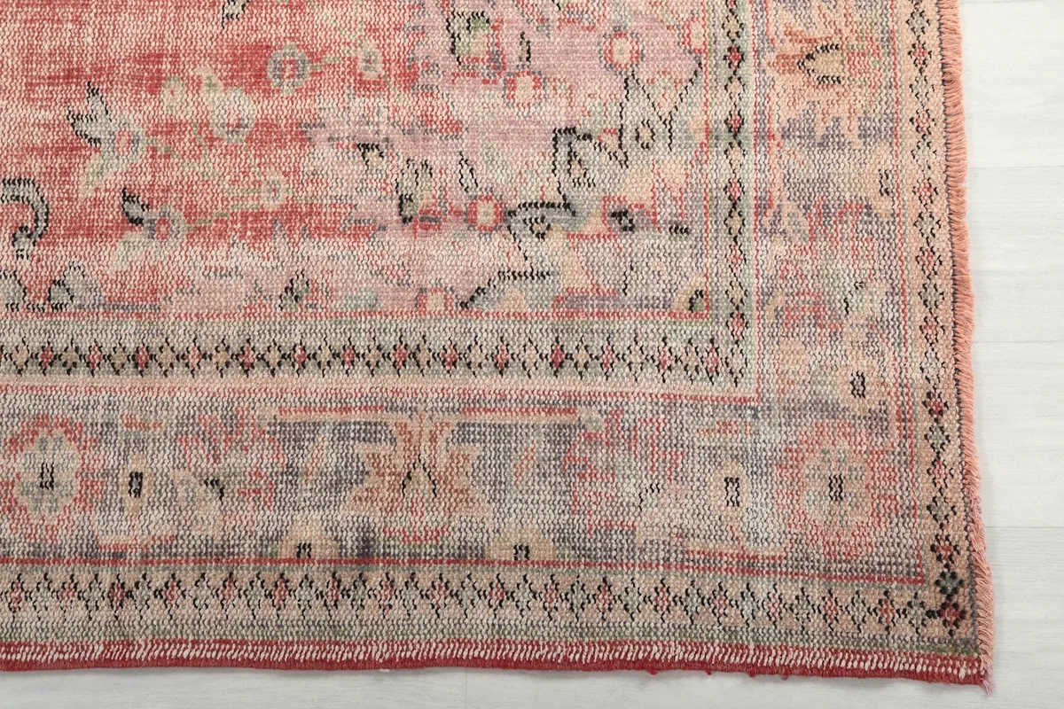 Close-up of the rug's border with intricate geometric patterns and blue accents