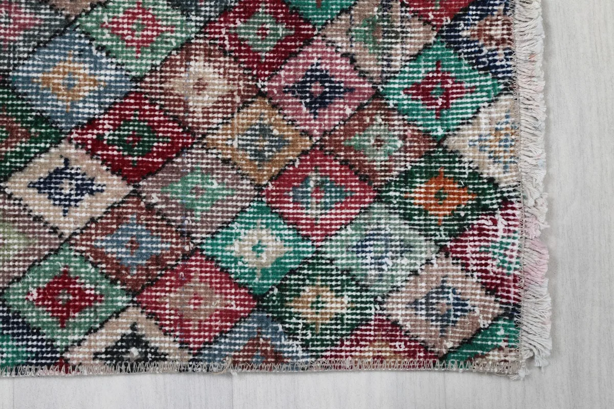 Detailed view of the multicolor diamond pattern and faded colors on the rug's edge