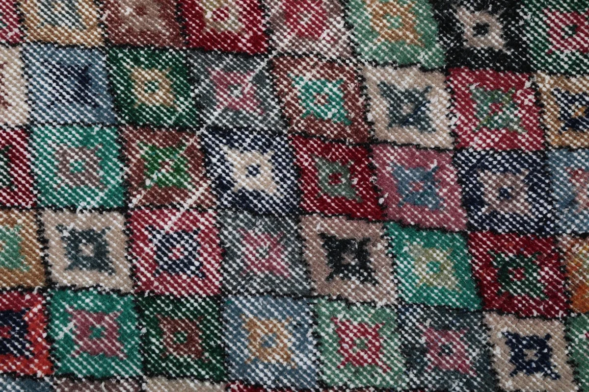 Extreme close-up of the hand-knotted wool pile and individual geometric motifs
