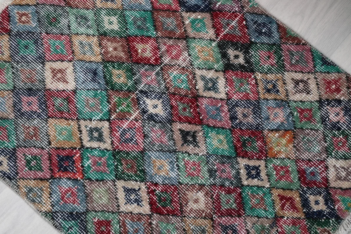 Overhead view showing the distressed texture and varied colored diamonds of the rug