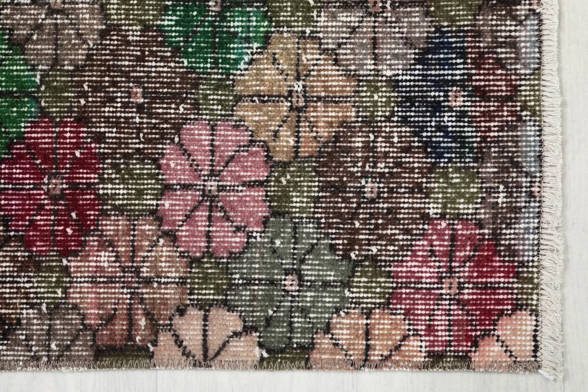 Detailed view of the rug's edge showing floral motifs in red, pink, green, and beige