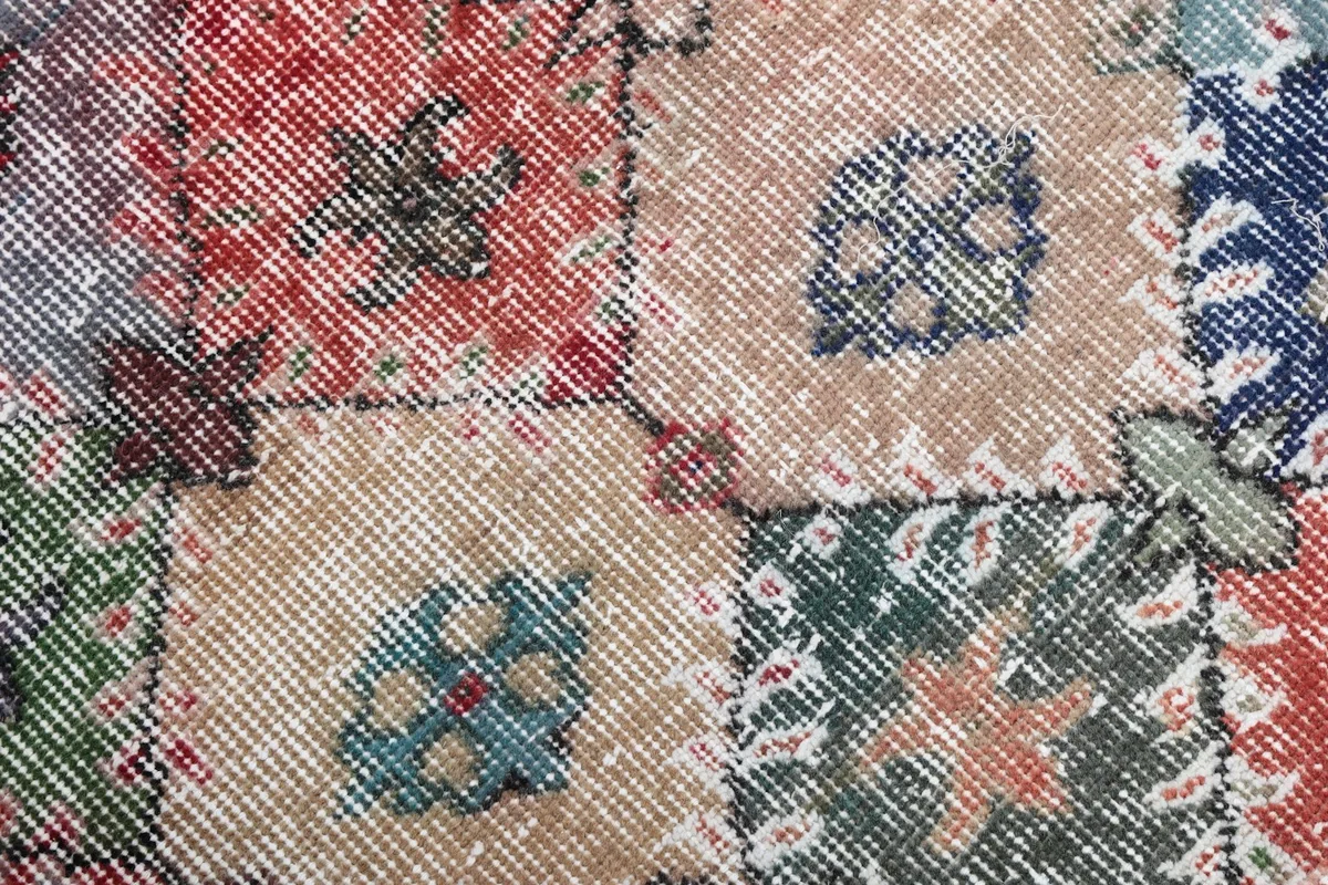 Close-up of the low wool pile and hand-knotted texture, revealing the distressed look and color variations