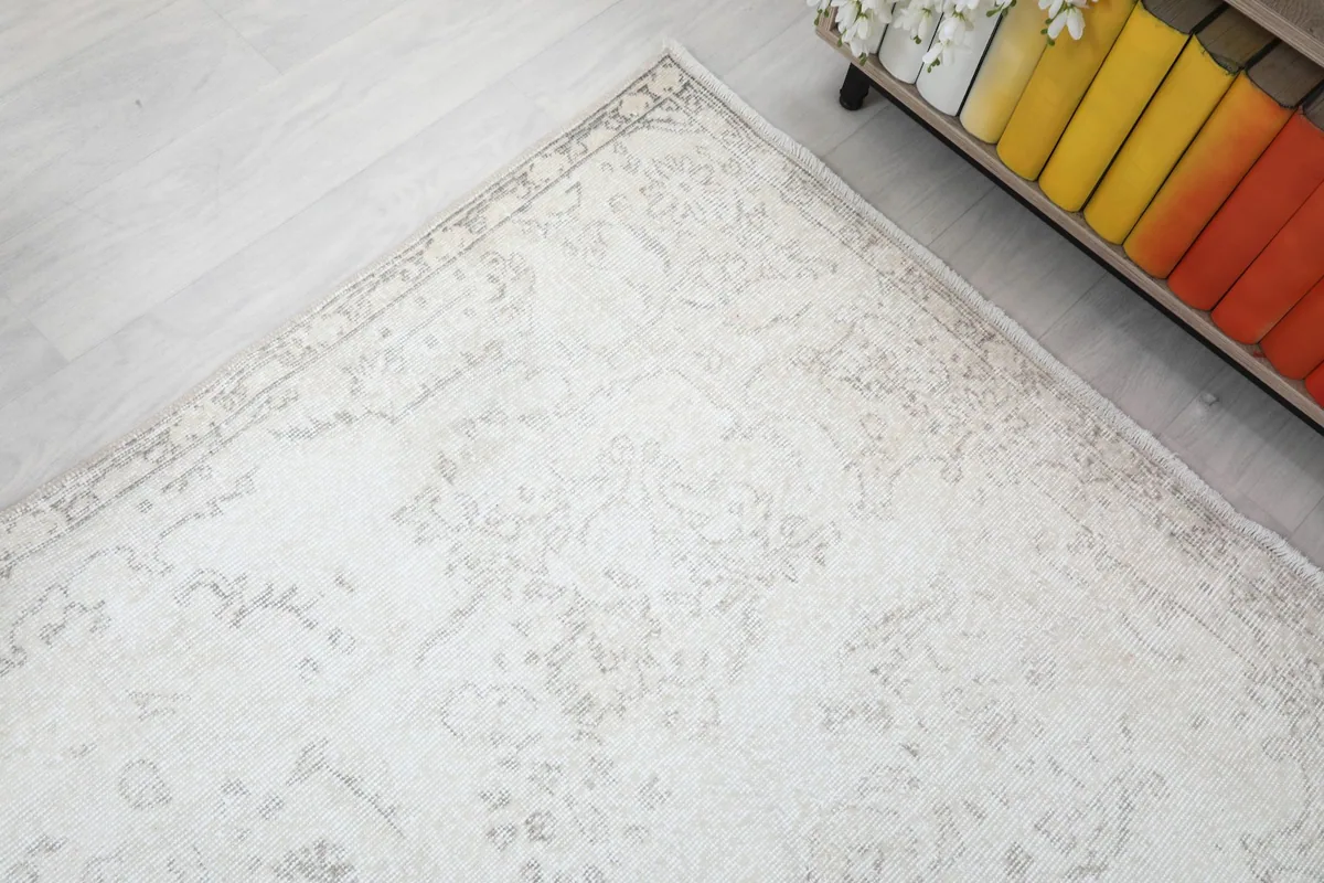Corner detail of the rug showing the border design and slight variations in the cream color