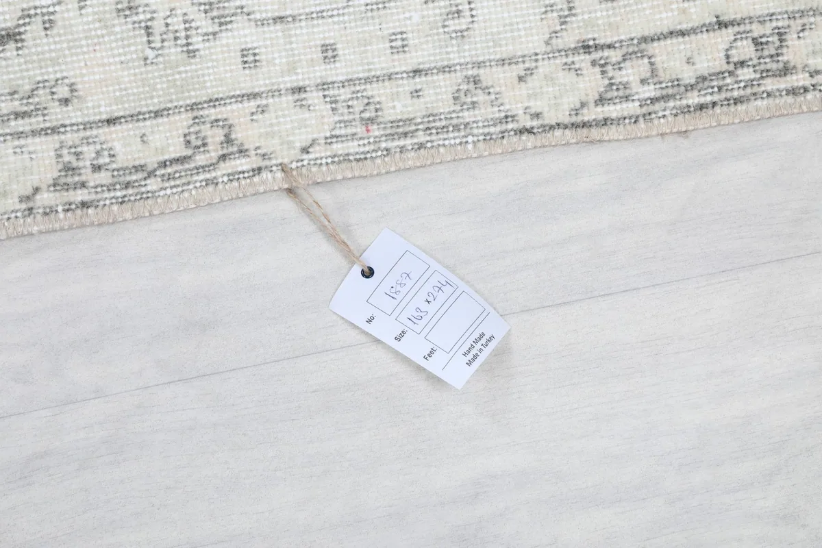 Product tag displaying rug dimensions and material information on the floor next to the rug