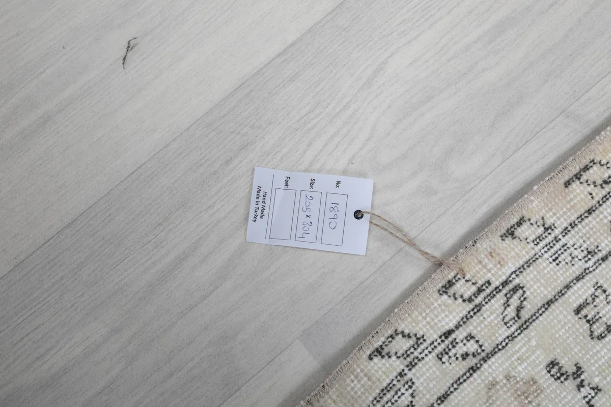 Product tag attached to the rug, displaying its details on a light wooden floor.