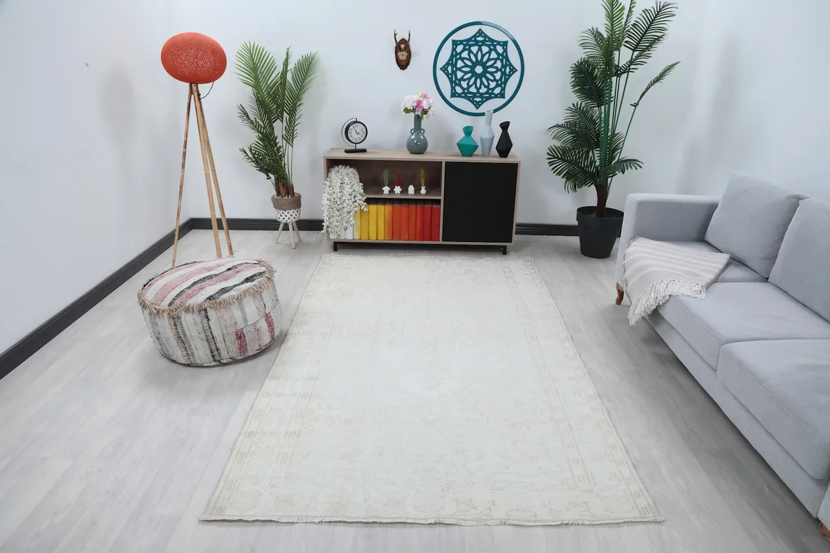 Ivory vintage rug placed in a modern living room setting with a gray sofa