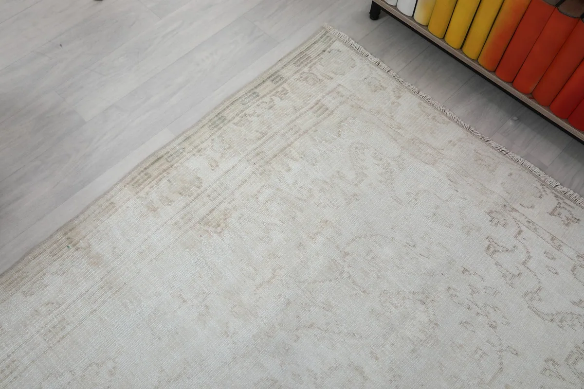Corner detail of the rug's faded border pattern and fringe