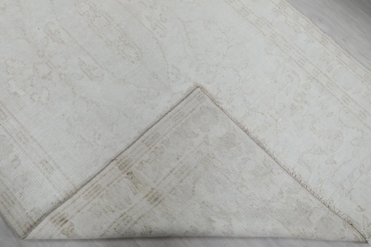 Folded corner of the rug revealing the hand-knotted cotton foundation underneath
