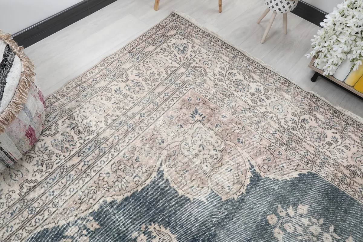 Corner view of the rug, illustrating the detailed border and the blend of ivory, beige, and gray tones.