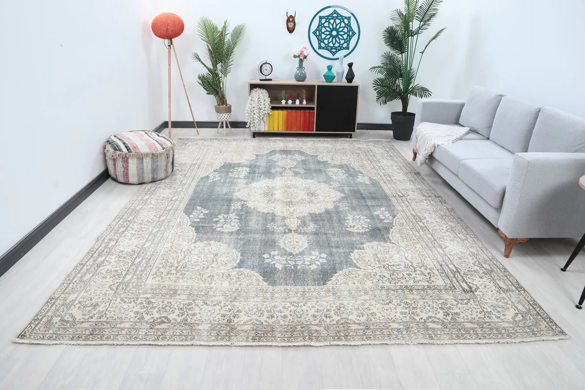 Large blue and ivory vintage rug placed in a living room setting with a light gray sofa and modern decor.