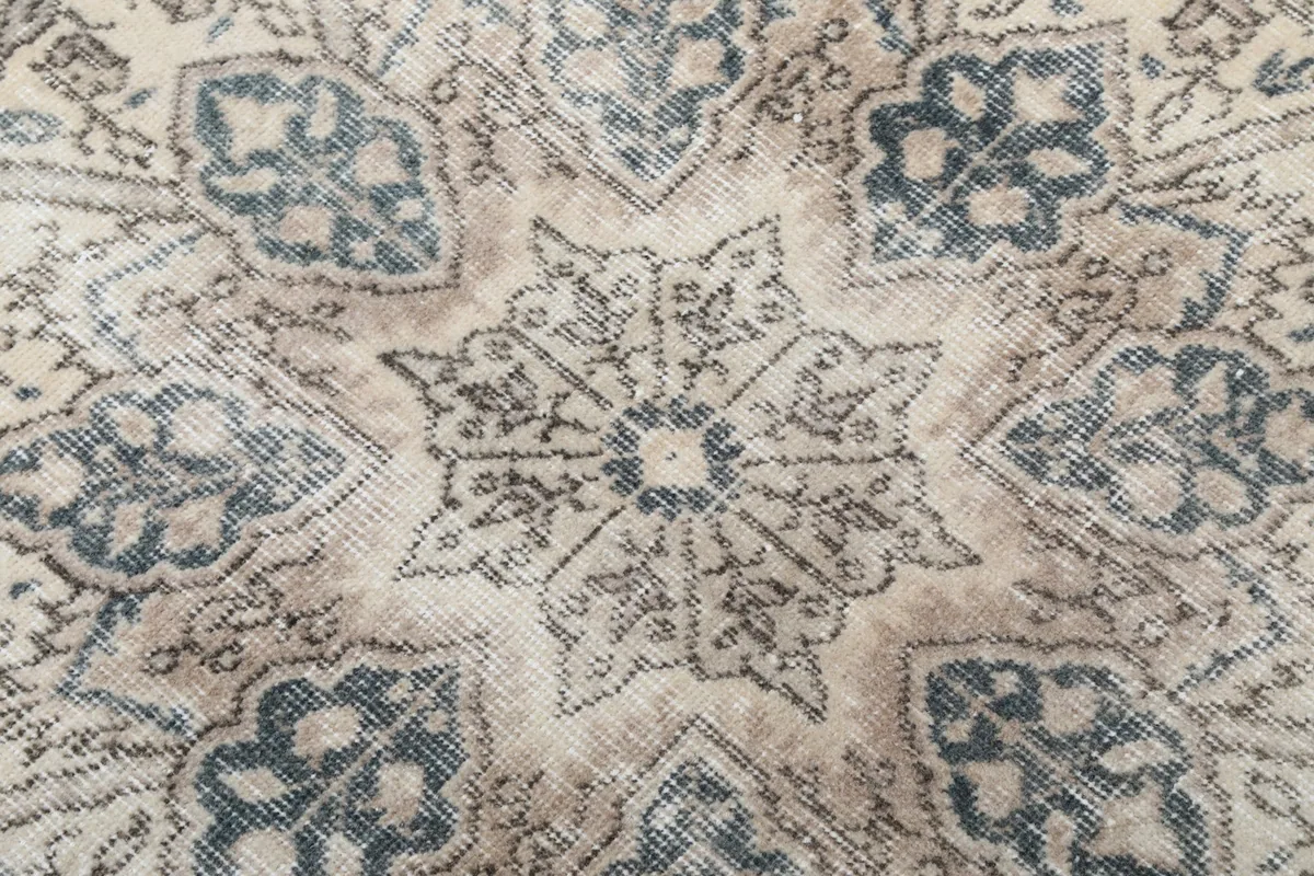 Extreme close-up of the medallion's core, revealing the fine knotting and subtle color variations in blue and beige.