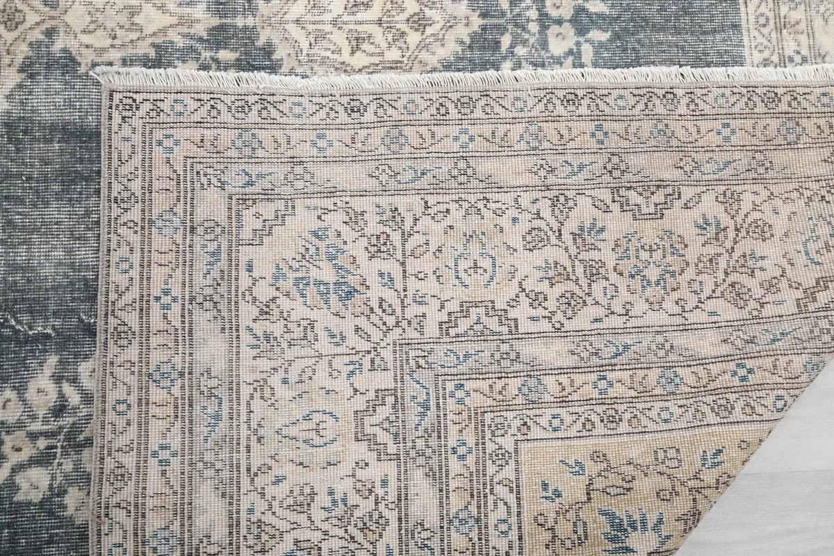 Close-up of the rug's edge, showing the short, natural fringes and the corner of the detailed border.