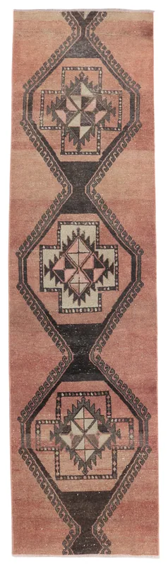 Full overhead view of the rose and black geometric Anatolian runner rug on a white background.