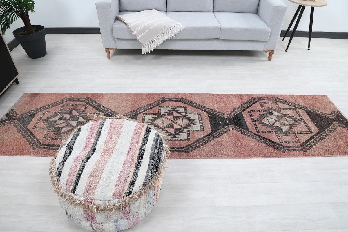 Full length view of the runner rug in a room setting with a sofa and pouf.