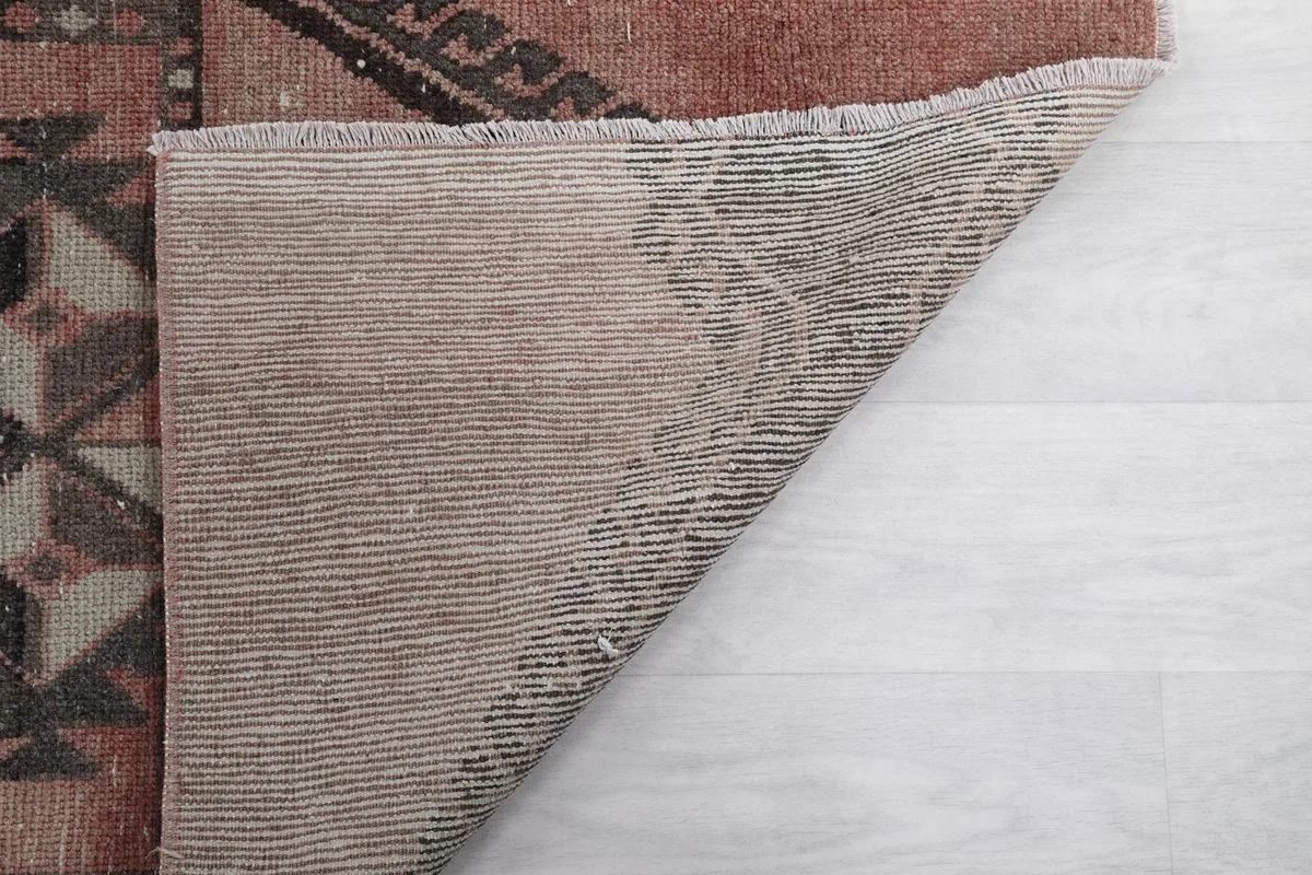 Partial view of the rug's back, showing the consistent weaving of the cotton foundation.
