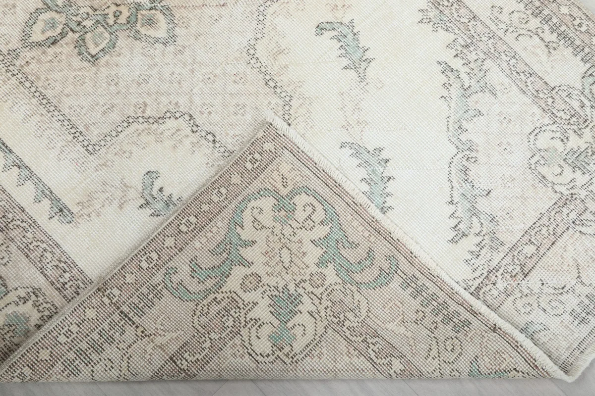 Corner of the rug folded back to show the cotton foundation and knotting