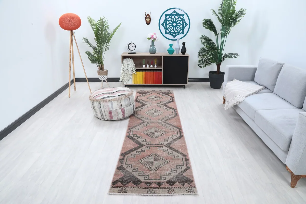 Vintage runner rug in a modern living space with a gray sofa and plants, showing its full length.