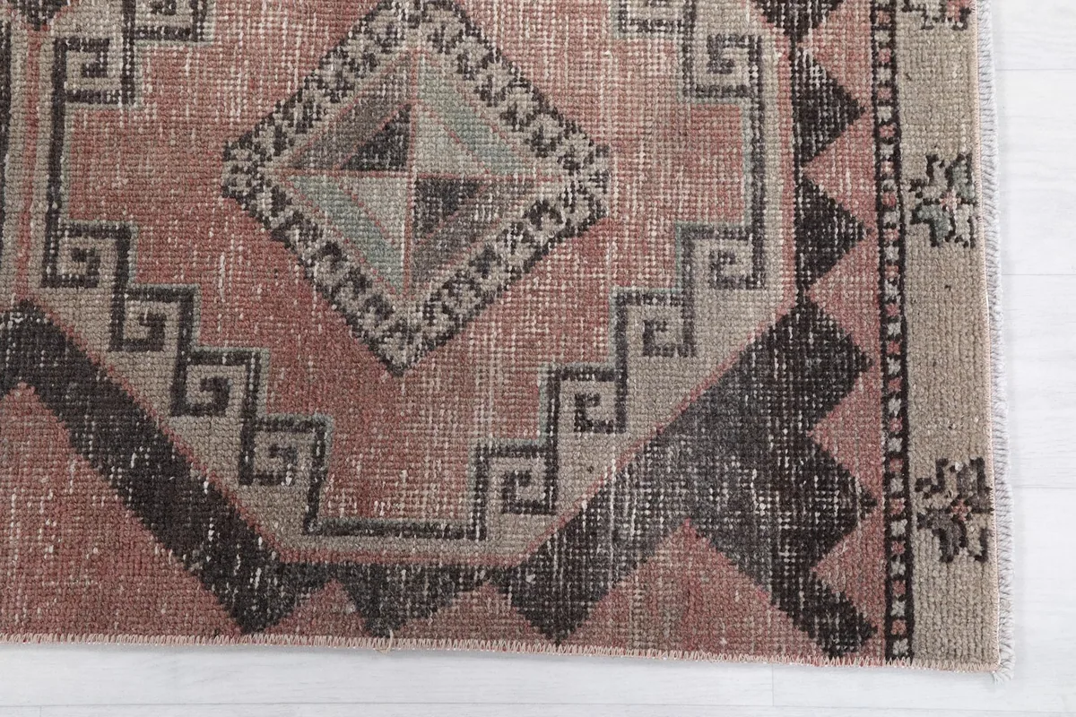 Detailed view of the rug's geometric patterns and color variations at one end.