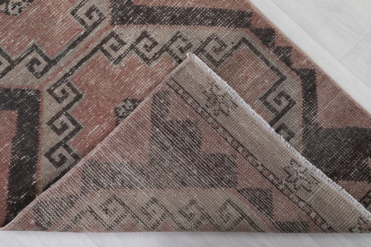 Corner of the rug folded back to reveal the hand-knotted cotton foundation and reverse side.
