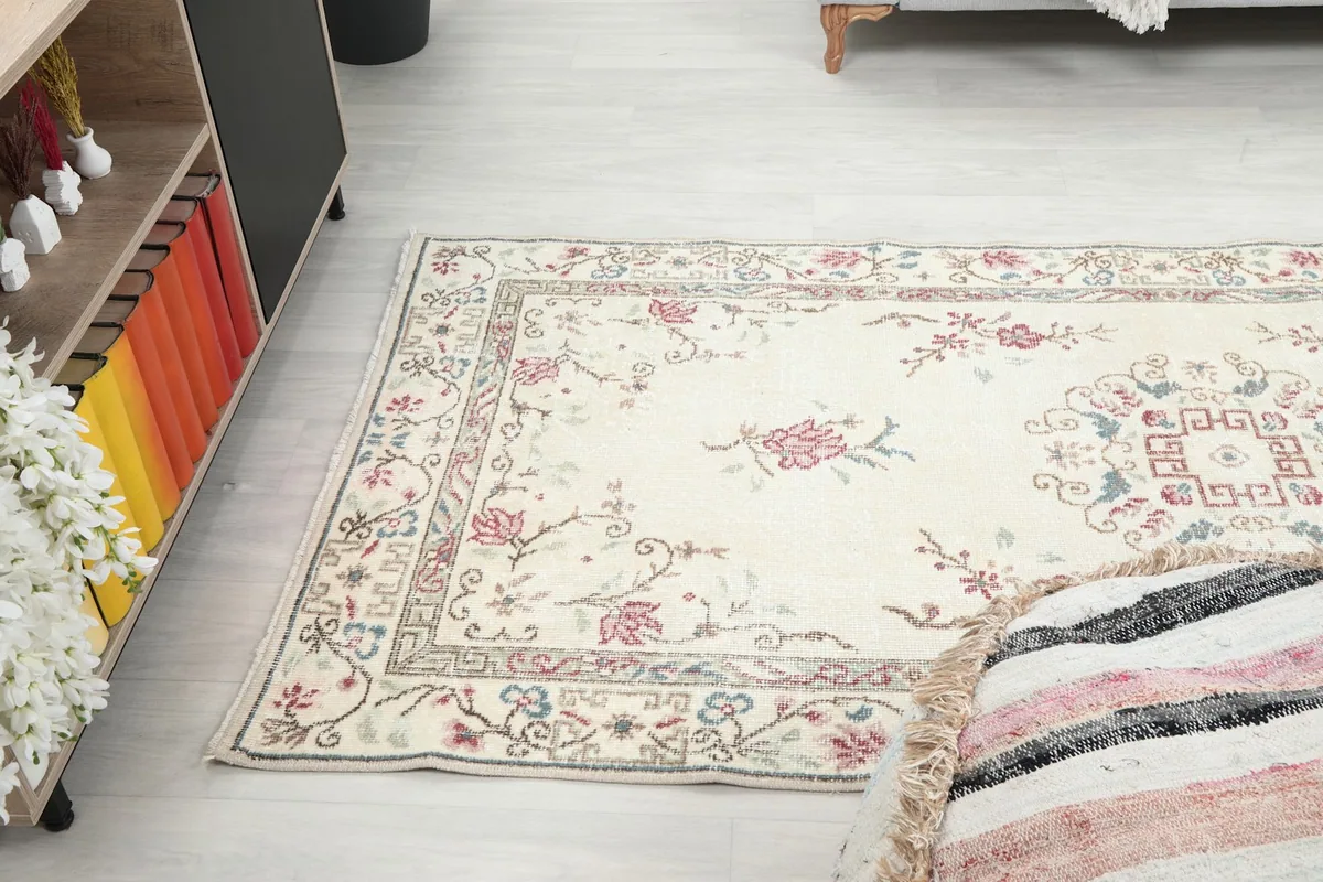 Angled view of the rug on the floor, capturing the floral design and ivory field