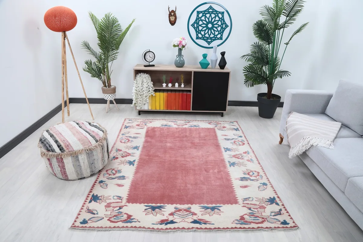 Rose and ivory vintage rug in a living room setting with plants and furniture