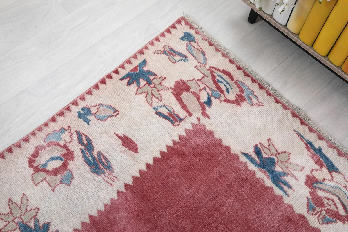 Corner detail of the rug's ivory border with blue and red floral patterns