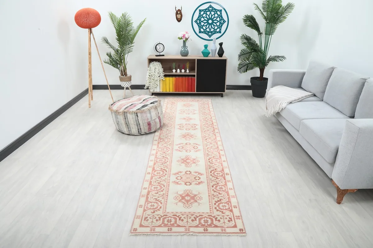 Vintage Anatolian runner rug displayed in a living room setting, showing its length next to a sofa.